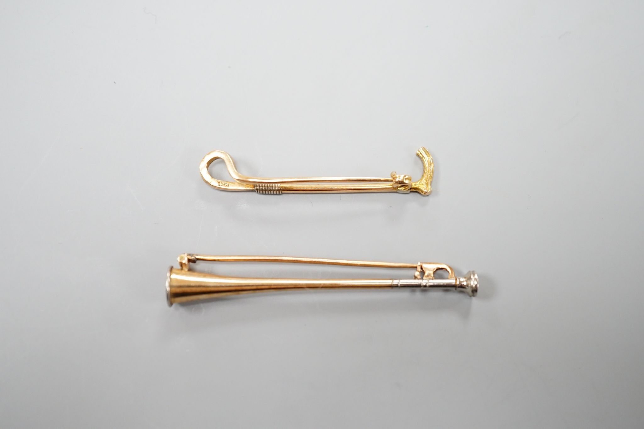 An Edwardian 15ct riding crop bar brooch, 44mm, 3.1 grams and a similar yellow and white metal hunting horn bar brooch, 56mm, gross 3.8 grams.